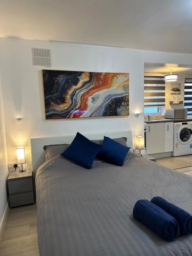 a bedroom with a large bed with blue pillows at Watford Junction, King Size Bed in Watford