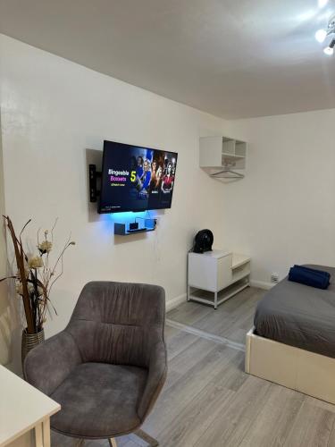 a living room with a chair and a tv on a wall at Watford Junction, King Size Bed in Watford