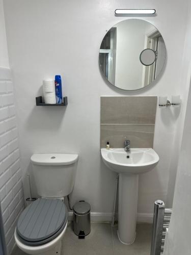 a bathroom with a toilet and a sink and a mirror at Watford Junction, King Size Bed in Watford