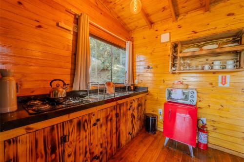 a kitchen with a red stove in a wooden cabin at Cascata dos Amores in Urubici