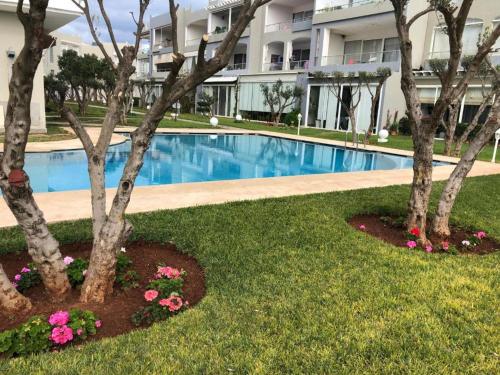 a swimming pool in front of a building with trees and flowers at Luxury Sea View in Tamaris