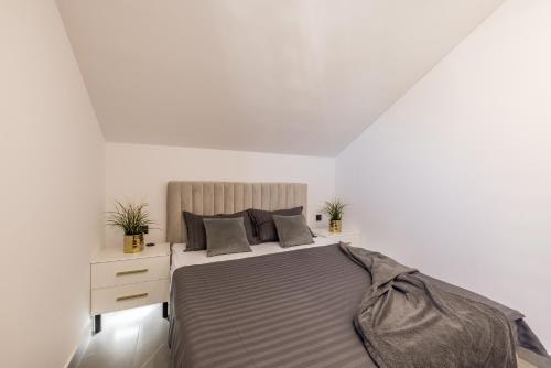 a white bedroom with a bed and a nightstand at Golden Sunset Sutivan - Exclusive 4-Star Apartment in Sutivan