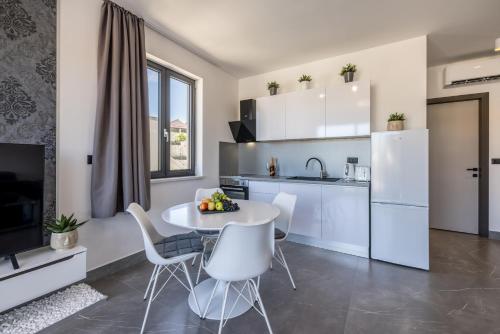 a kitchen with a table and chairs and a kitchen with white appliances at Golden Sunset Sutivan - Exclusive 4-Star Apartment in Sutivan