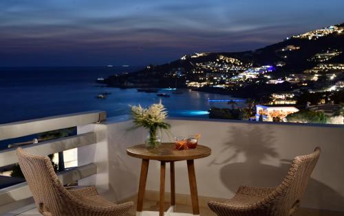 a table on a balcony with a view of the ocean at Anax Resort and Spa in Agios Ioannis Mykonos