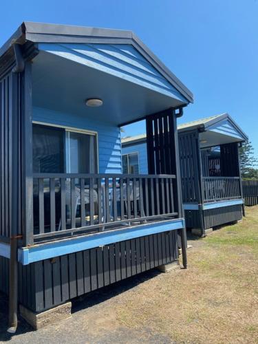 a blue house with a porch and a bench at Absolute Oceanfront Tourist Park in Bargara