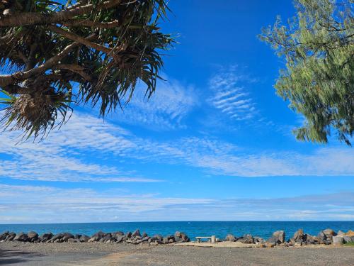 a group of rocks on a beach with a bench at Absolute Oceanfront Tourist Park in Bargara