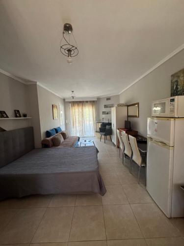 a bedroom with a bed and a desk and a refrigerator at Roses Apartments in Néa Michanióna