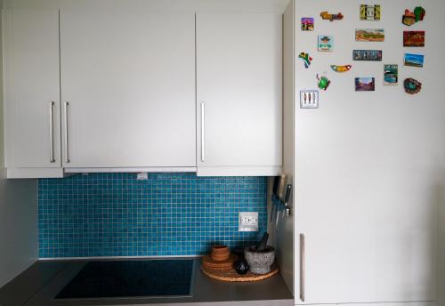 a kitchen with white cabinets and blue tile at Solrik leilighet på Byåsen in Trondheim