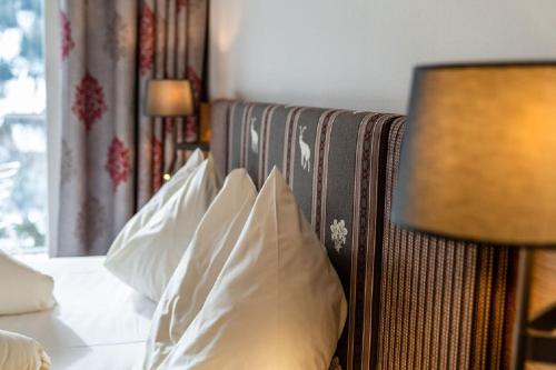 sypialnia z łóżkiem z białymi poduszkami i lampą w obiekcie Aktivhotel Pehab w mieście Ramsau am Dachstein