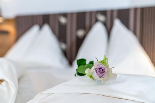 kwiat na łóżku z białymi poduszkami w obiekcie Aktivhotel Pehab w mieście Ramsau am Dachstein