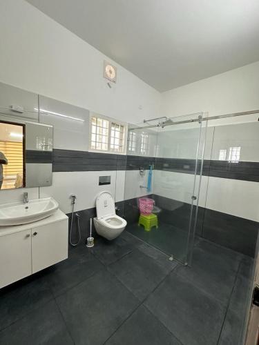 a bathroom with a toilet and a sink and a shower at Cozy Homestays in Ernakulam