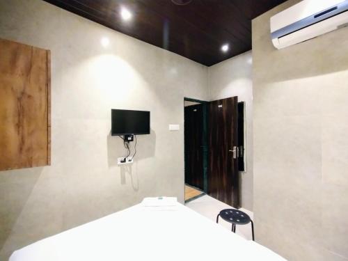 a bedroom with a bed and a tv on the wall at Hotel Eros - Nr Airport T2 in Mumbai