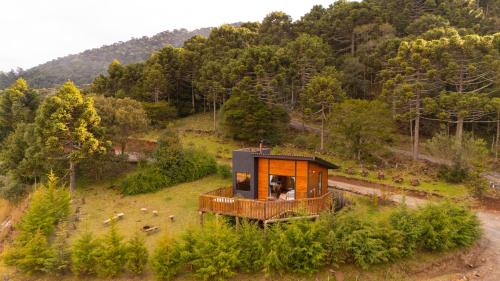 a tiny house on top of a hill with trees at Cascata dos Amores in Urubici