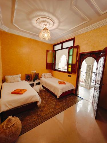 two beds in a room with yellow walls at Riad Noor in Agadir
