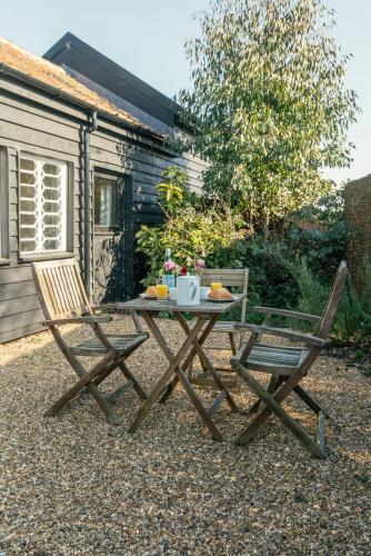 a picnic table and two chairs in front of a cabin at 1 Henham Barns in Beccles