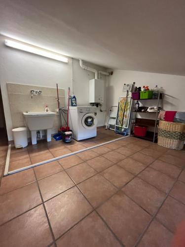 a bathroom with a sink and a washing machine at Appartamento Mansarda nel verde in Tavullia