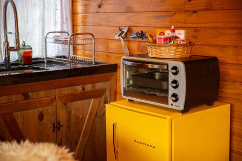 a microwave on top of a yellow refrigerator in a kitchen at Cascata dos Amores in Urubici