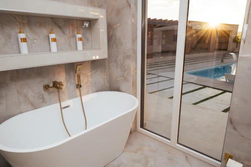 a bathroom with a bath tub next to a glass door at Golden View Villa Sauna & Spa in Blagaj