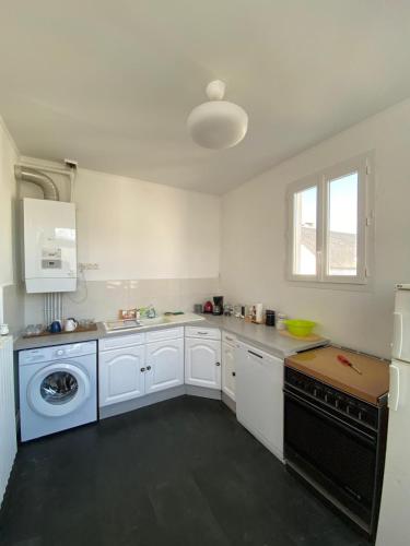 une cuisine avec des armoires blanches et un lave-vaisselle noir dans l'établissement Cocon Appartement Hyper-centre proche plage et marché - 2 chambres, au Pouliguen