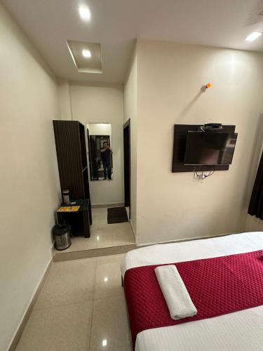 a room with a bed and a tv and a mirror at Hotel Gopal in Haridwār