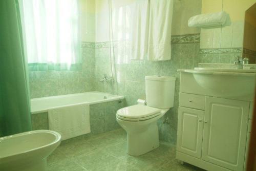 een badkamer met een toilet, een wastafel en een bad bij Hotel Portas Do Dao in Penalva do Castelo