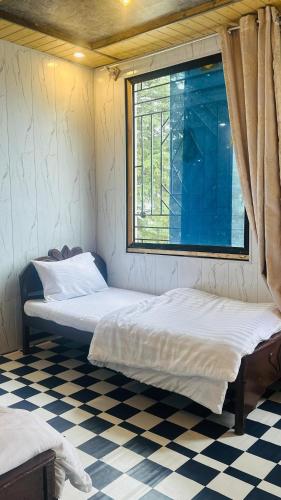 two beds in a room with a window and a checkered floor at FOG LAND GUEST HOUSE nathia gali kala bagh in Nathia Gali