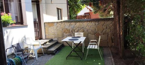 a table and chairs on a patio next to a stone wall at Za Rabą Nowy in Myślenice