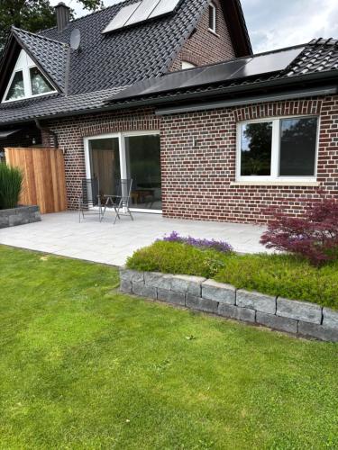 a brick house with a patio and a yard at Fewo Oster in Ochtrup