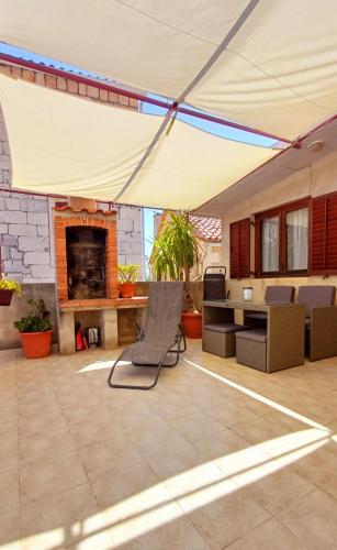 a patio under a tent with a chair and a fireplace at Apartment Diana in Komiža