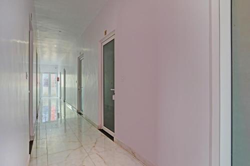 BhauliHotel O Mb Garden & Resorts的一条带白色墙壁和黑色门的走廊