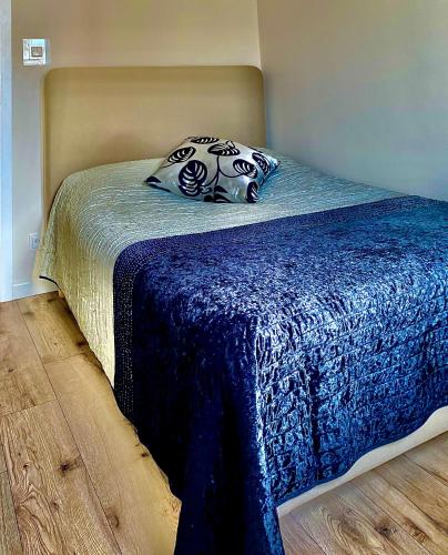 a bed with a blue blanket and pillows on it at Apartament Gruszowe Sady Nowaka 6 in Olsztyn