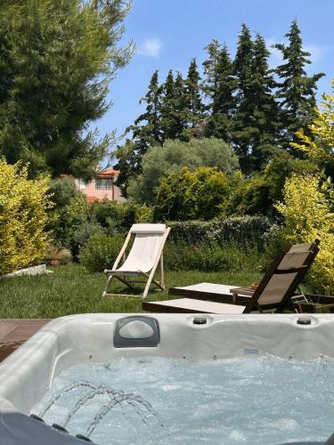 a hot tub in a yard with two chairs at Pelagus Luxury Villas in Polykhrono