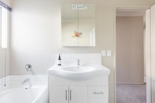 a white bathroom with a sink and a tub at Room in Wellington in Porirua