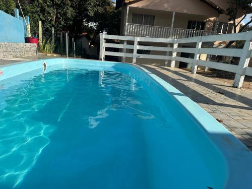 a large blue swimming pool next to a white fence at Pousada Cipó in Serra do Cipo