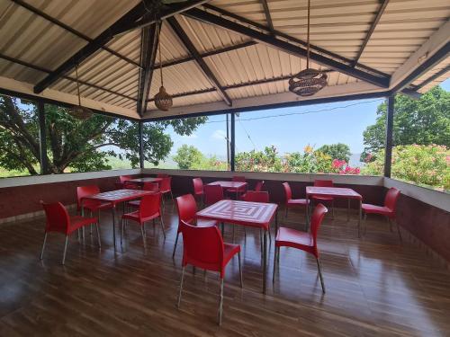 a restaurant with red chairs and tables and windows at Shalgar Villa The Homestay in Satara