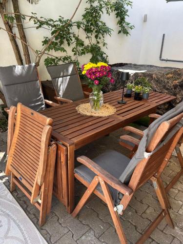 a wooden table with chairs and a vase of flowers at Ferienwohnung LandLeben für 2-3 Personen in Edesheim