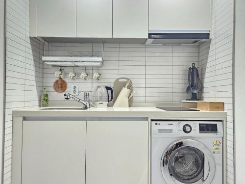 a kitchen with a washing machine and a sink at Shinhwahouse 5 mins from Seoul Station in Seoul