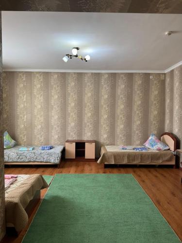 a living room with two beds and a green rug at Гостиница Асем-Ай in Taraz