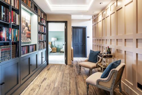 a hallway with bookshelves and chairs in a home library at Kingsley House in Haslemere