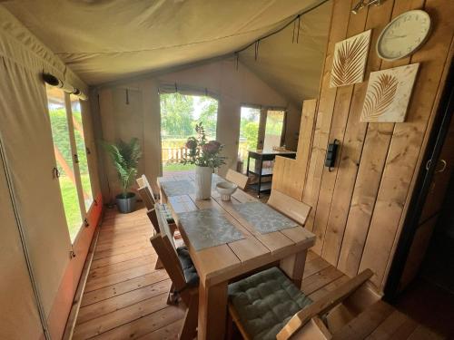 a dining room with a wooden table and chairs at Safari-Zelt Am Landwehrsee in Dörverden