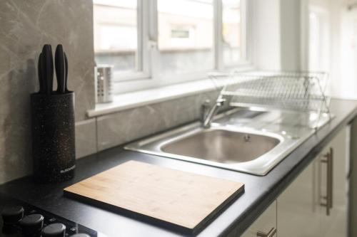 - un comptoir de cuisine avec un évier et une planche de coupe dans l'établissement Contractor Stay Cardiff 3 Bedroom House with Parking, à Cardiff