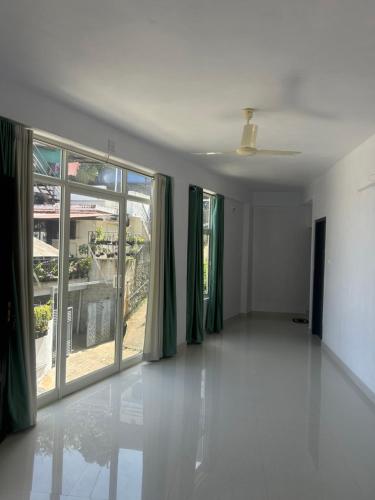 an empty room with a large window with green curtains at Samriddhi Homestay in Trivandrum