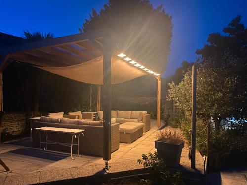 a pergola with a couch and a table under it at L'hébergerie sablotine in Chaillé-les-Marais