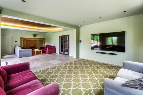 a living room with purple furniture and a flat screen tv at Kingsley House in Haslemere