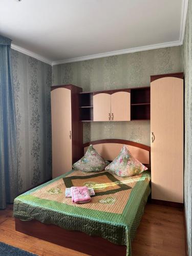a bedroom with a bed with pink and green sheets at Гостиница Асем-Ай in Taraz