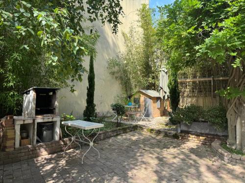 a backyard with an oven and a table and trees at Côté Cour - Studio voûté by PRIM0 C0NCIERGERIE in Aubière