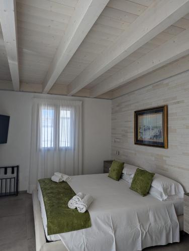 a bedroom with a large white bed with green pillows at Al Corso Charming Rooms in Peschici