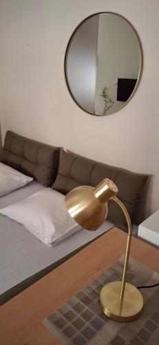 Una lámpara dorada frente a una cama con un espejo. en Felicia Apartments, en Budva
