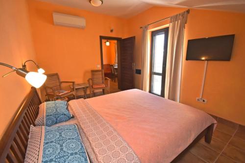 a bedroom with a bed and a room with a television at Falcone Apartments in Ðenovići