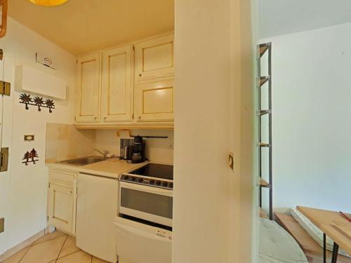 une cuisine avec des armoires blanches et un four à plaques de cuisson dans l'établissement Studio - 4 pers, Le Grand-Bornand, commerces à pied, parking couvert - FR-1-241-216, au Grand-Bornand